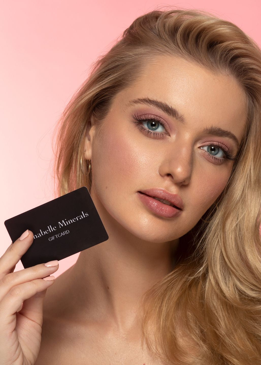 Modelka prezentująca kartę podarunkową Annabelle Minerals na różowym tle